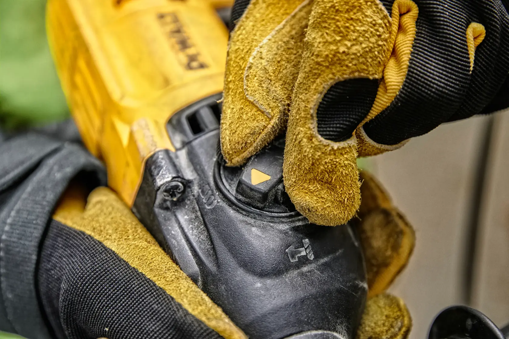 Nahaufnahme einer Person mit gelb-schwarzen Arbeitshandschuhen, die den Moduswahlschalter an einem DEWALT Elektrowerkzeug einstellt.