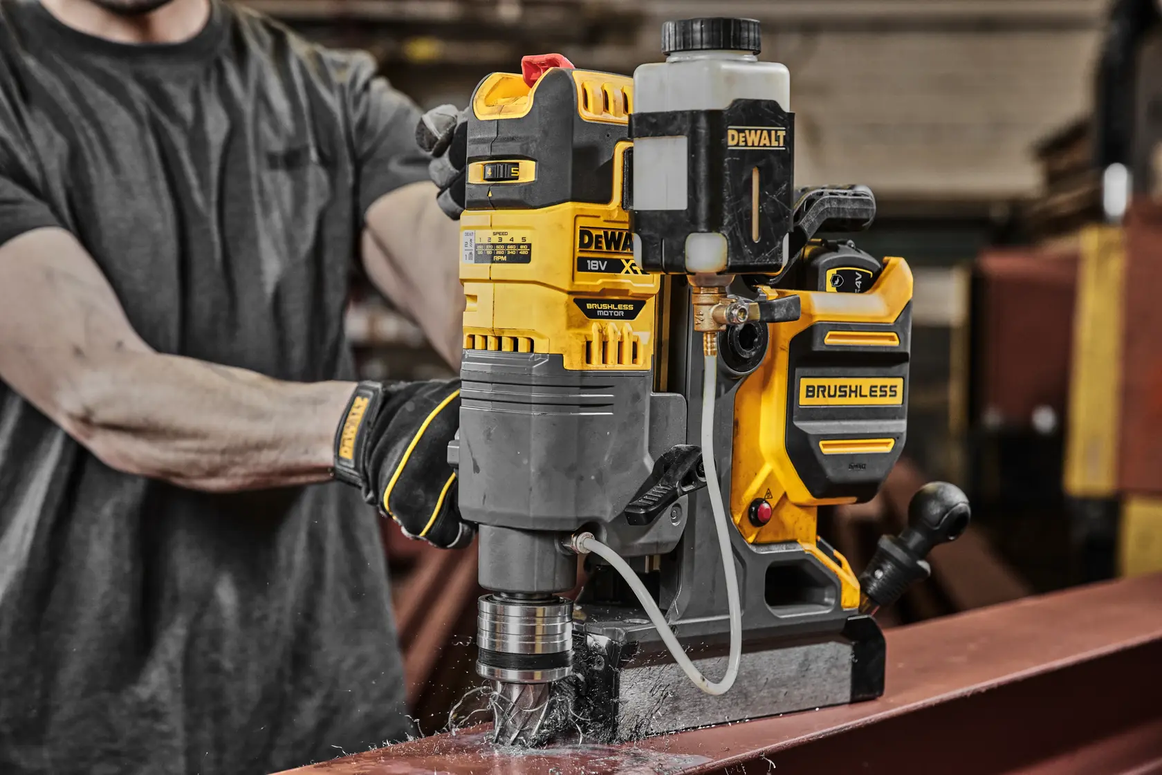 Taladro magnético sin escobillas DEWALT perfora viga de acero en taller industrial.
