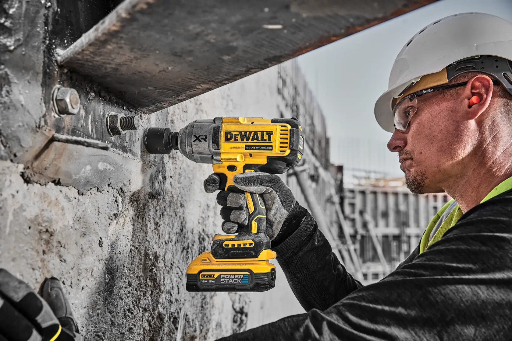 Operaio usa un avvitatore a impulsi DEWALT su struttura in cemento in cantiere.
