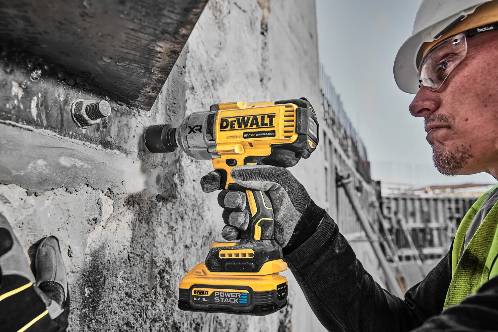 Operaio usa avvitatore a impulsi DEWALT DCF900H2T giallo su cemento in cantiere.