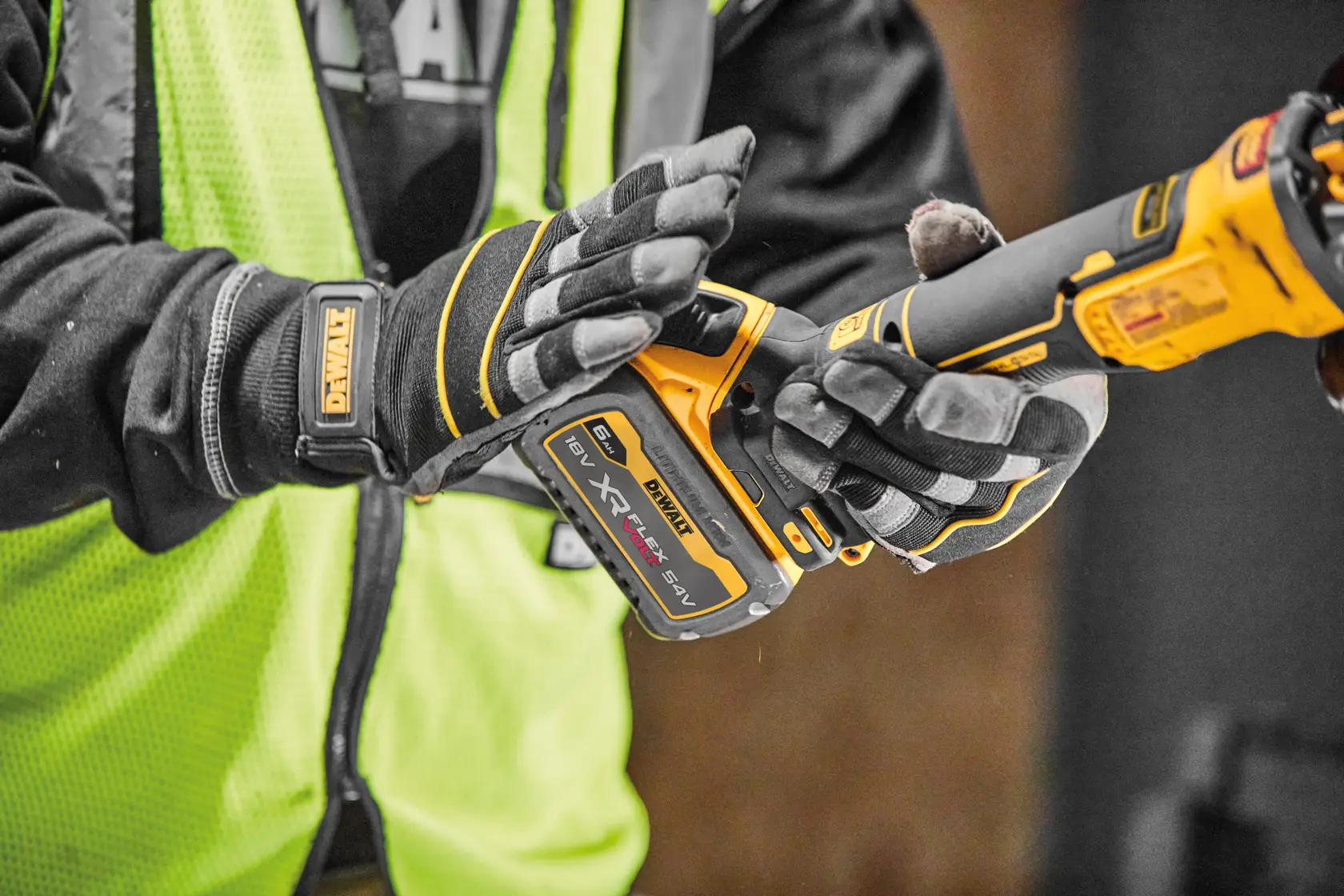 Persona con guanti tiene utensile DEWALT XR FLEXVOLT senza fili, con gilet di sicurezza giallo.
