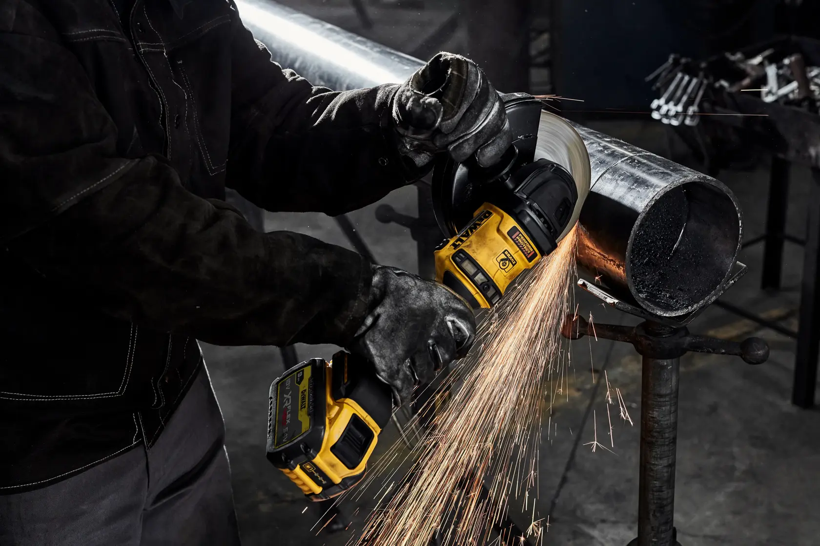 Persona taglia un tubo metallico con smerigliatrice DEWALT, scintille in ambiente industriale.