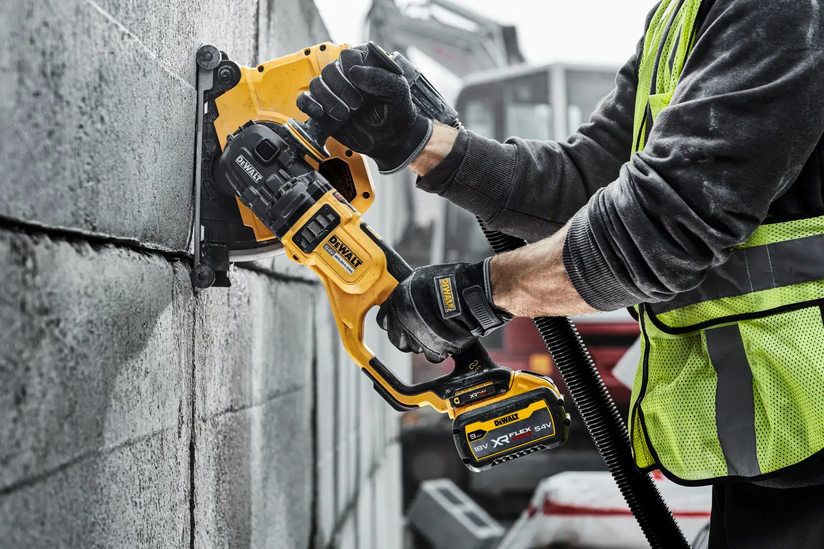 Operaio usa una scanalatrice DEWALT a batteria per tagliare scanalature sul muro in cemento.