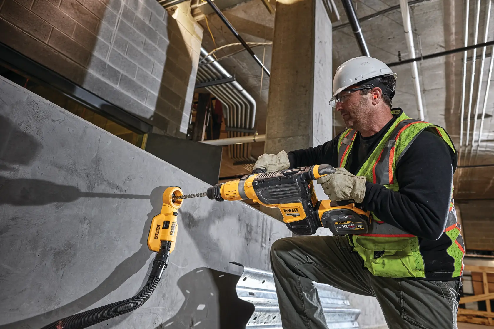 Operaio usa il martello rotante DEWALT DCH773N su muro di cemento in cantiere.