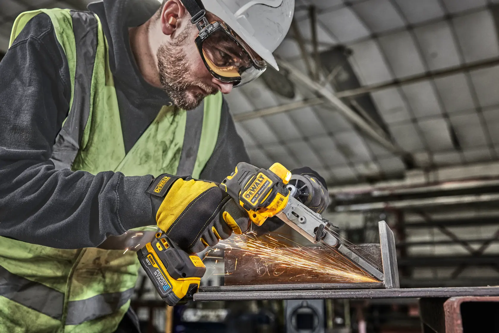 Operaio usa DEWALT DCM200E2T per smerigliare metallo con scintille in un'officina industriale.