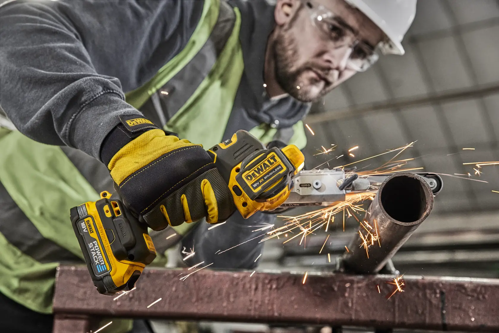 Operaio taglia un tubo d'acciaio con DEWALT senza fili, scintille sul posto di lavoro.