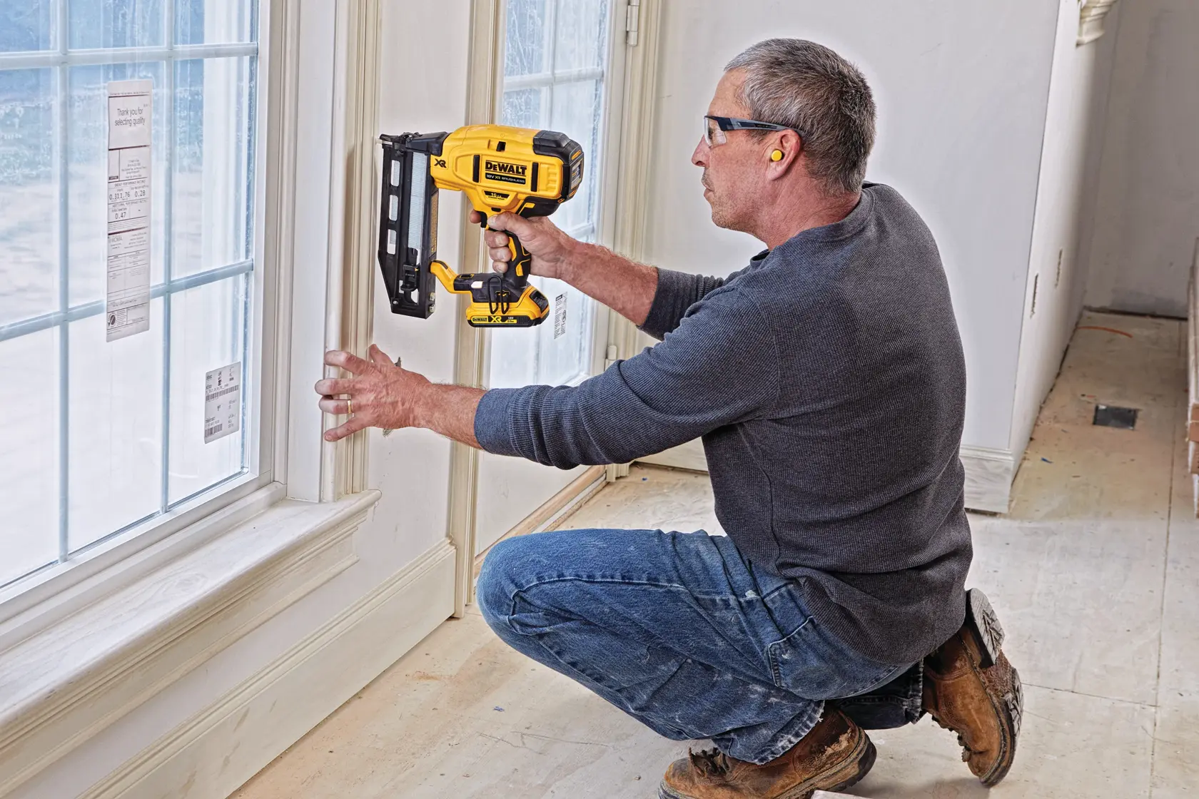 Persona usa una chiodatrice DEWALT DCN662D2 su una finestra in una stanza in costruzione.
