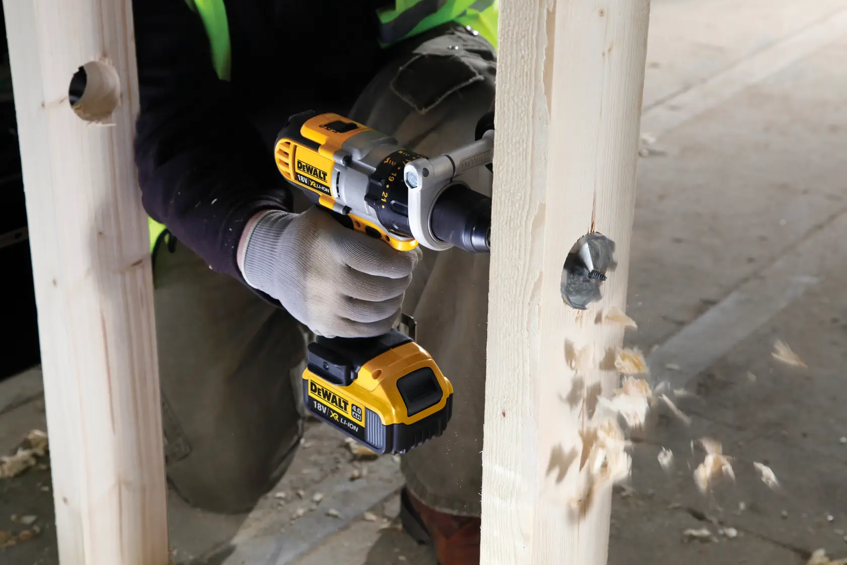 Trapano DEWALT in uso, crea un foro in una trave di legno, schegge volano durante la foratura.