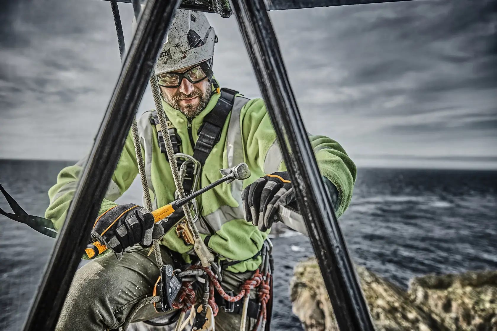 Operaio con equipaggiamento di sicurezza usa martello DEWALT all'aperto vicino all'acqua e struttura metallica.