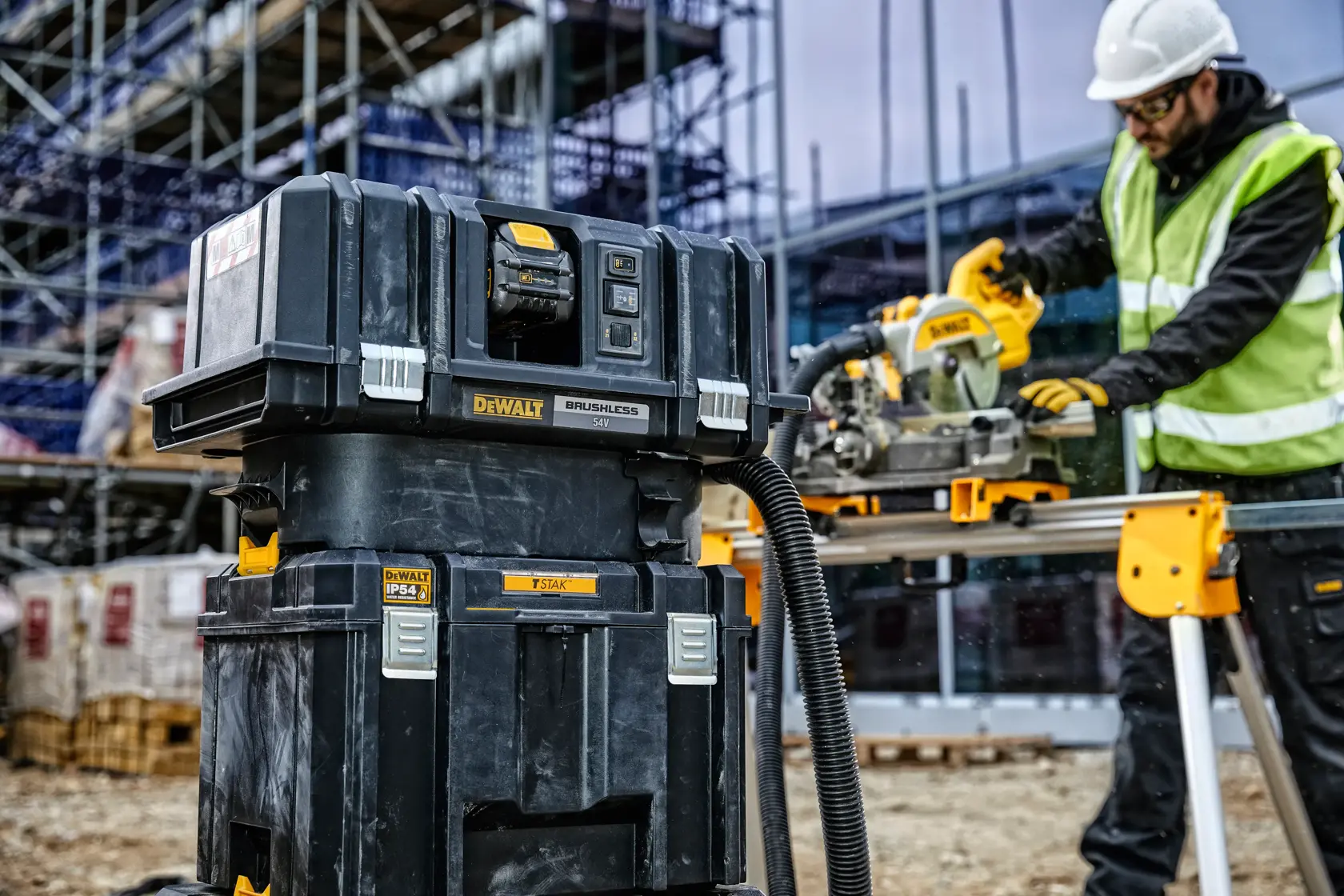 Sistema di stoccaggio e aspirazione DEWALT in cantiere, operatore usa utensile sullo sfondo.